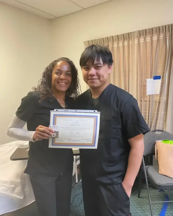 Instructor Tynesha Zacarias presenting a graduate with his certificate of completion